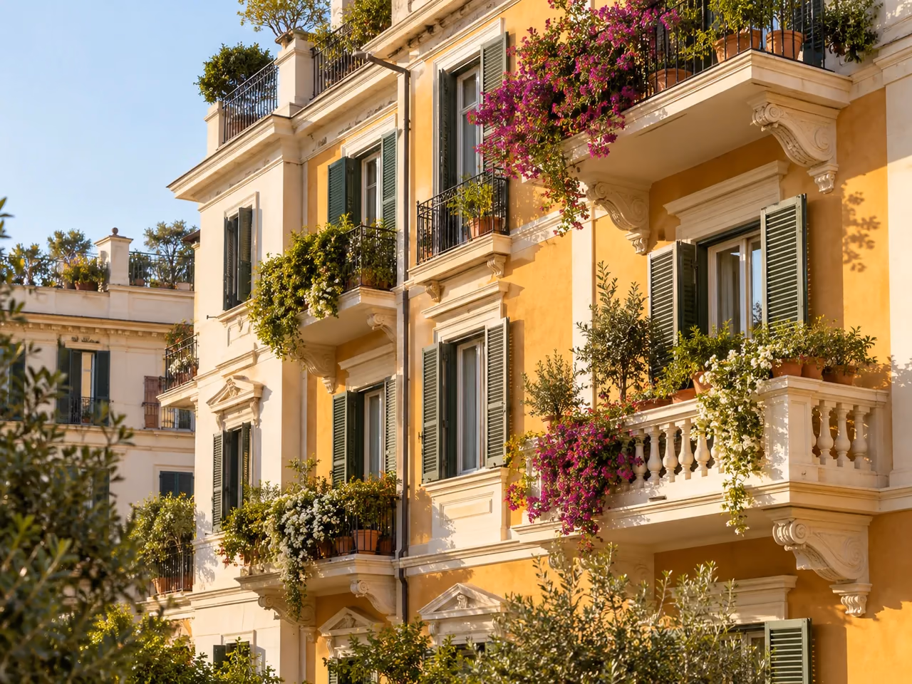 Fachada de pisos mediterráneos con balcones y persianas verdes